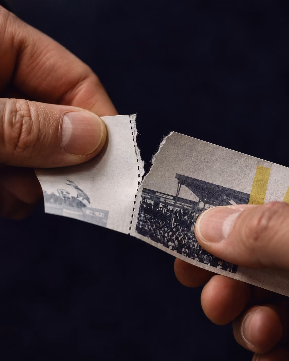 Two hands tearing a printed ticket along its perforation